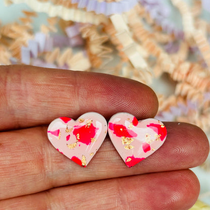 Vibrant pink heart-shaped stud earrings, handmade with polymer clay. Features rose gold leaf accents.