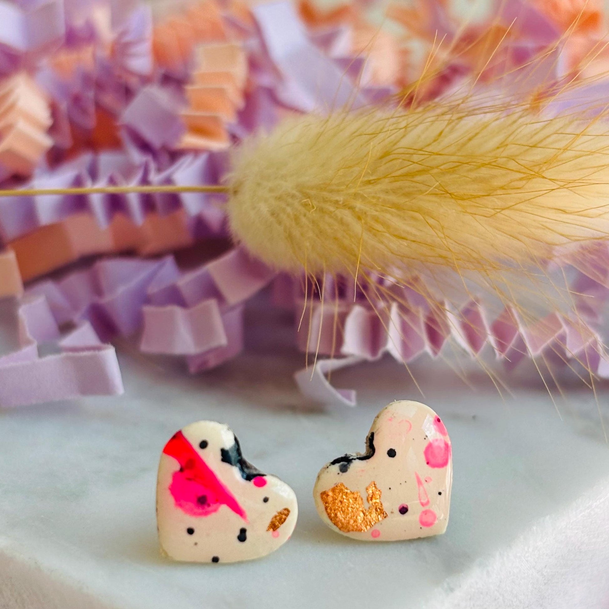 Quirky 90s-inspired neon pink heart-shaped stud earrings, handmade with polymer clay.