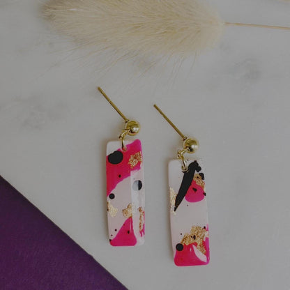 Edgy drop stud earrings with a unique design featuring white, neon pink, rose gold foil, and black ink, handmade with polymer clay.