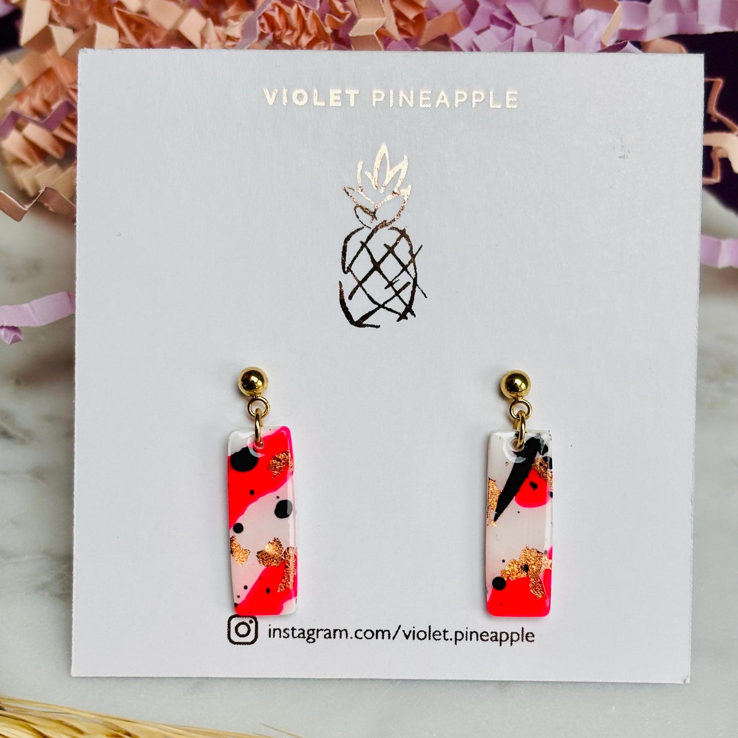 Edgy drop stud earrings with a unique design featuring white, neon pink, rose gold foil, and black ink, handmade with polymer clay.