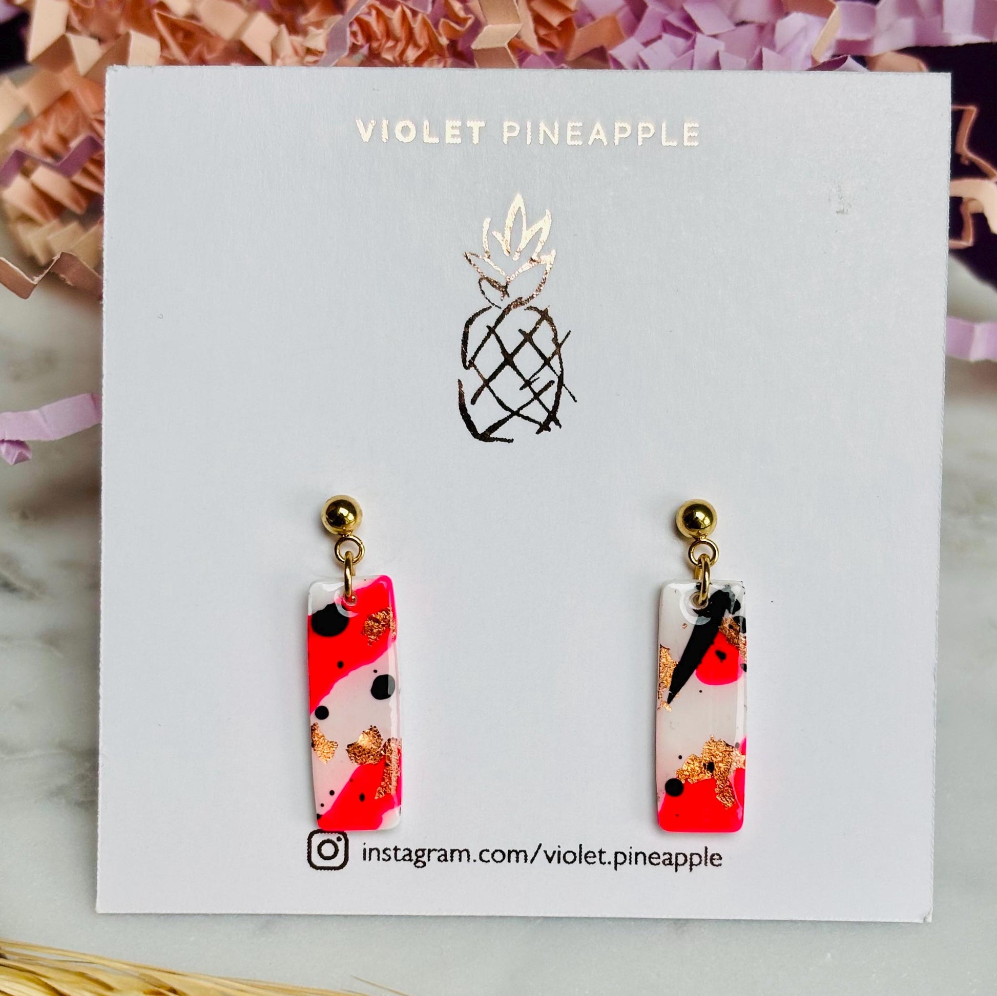 Edgy drop stud earrings with a unique design featuring white, neon pink, rose gold foil, and black ink, handmade with polymer clay.