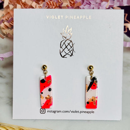 Edgy drop stud earrings with a unique design featuring white, neon pink, rose gold foil, and black ink, handmade with polymer clay.