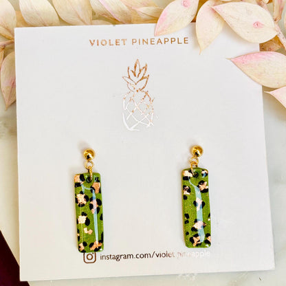 Elegant leopard print drop earrings with gold foil accents, hand-painted and handmade with polymer clay.