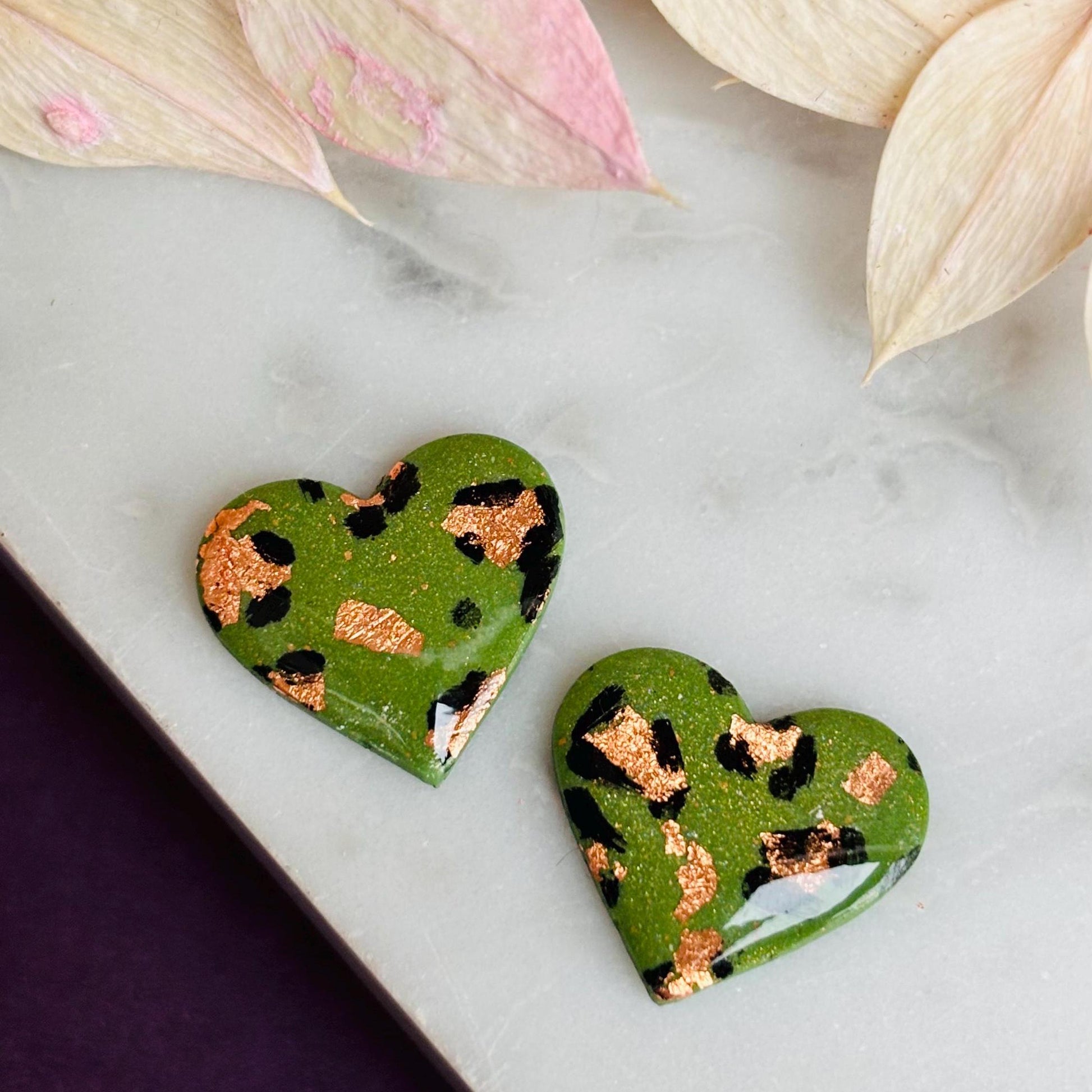 Elegant heart-shaped stud earrings with a hand-painted leopard print, handmade with polymer clay.