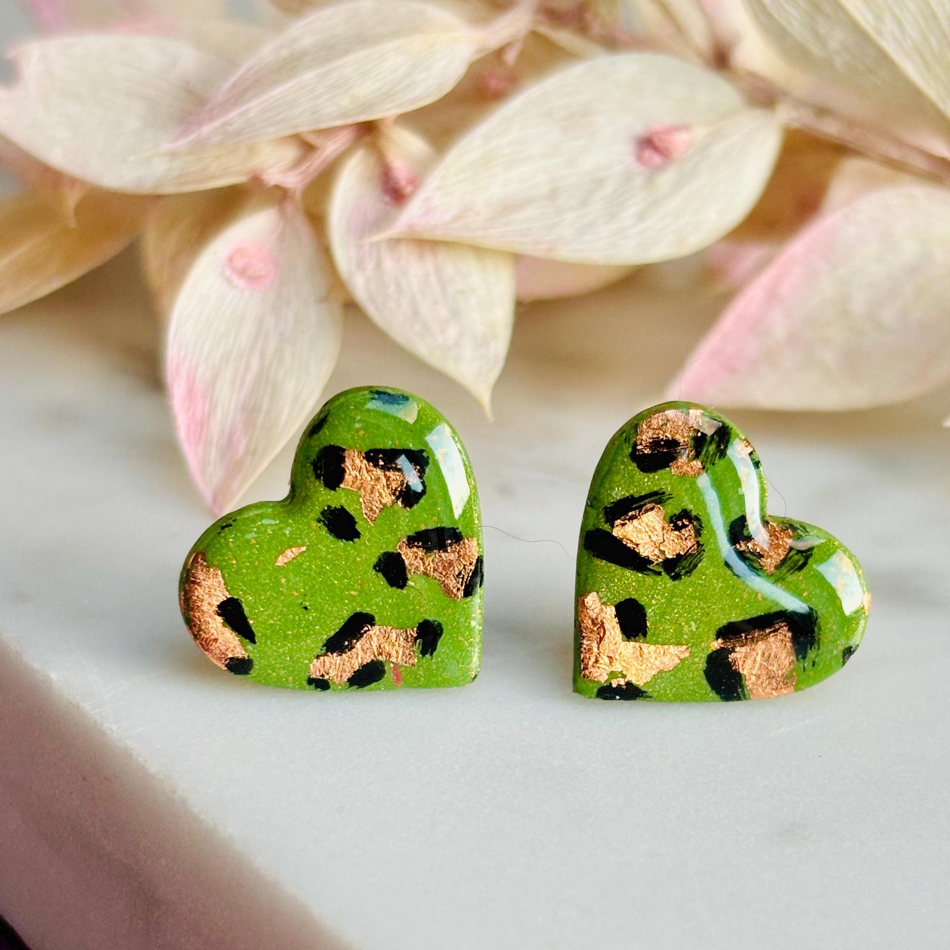 Elegant heart-shaped stud earrings with a hand-painted leopard print, handmade with polymer clay.