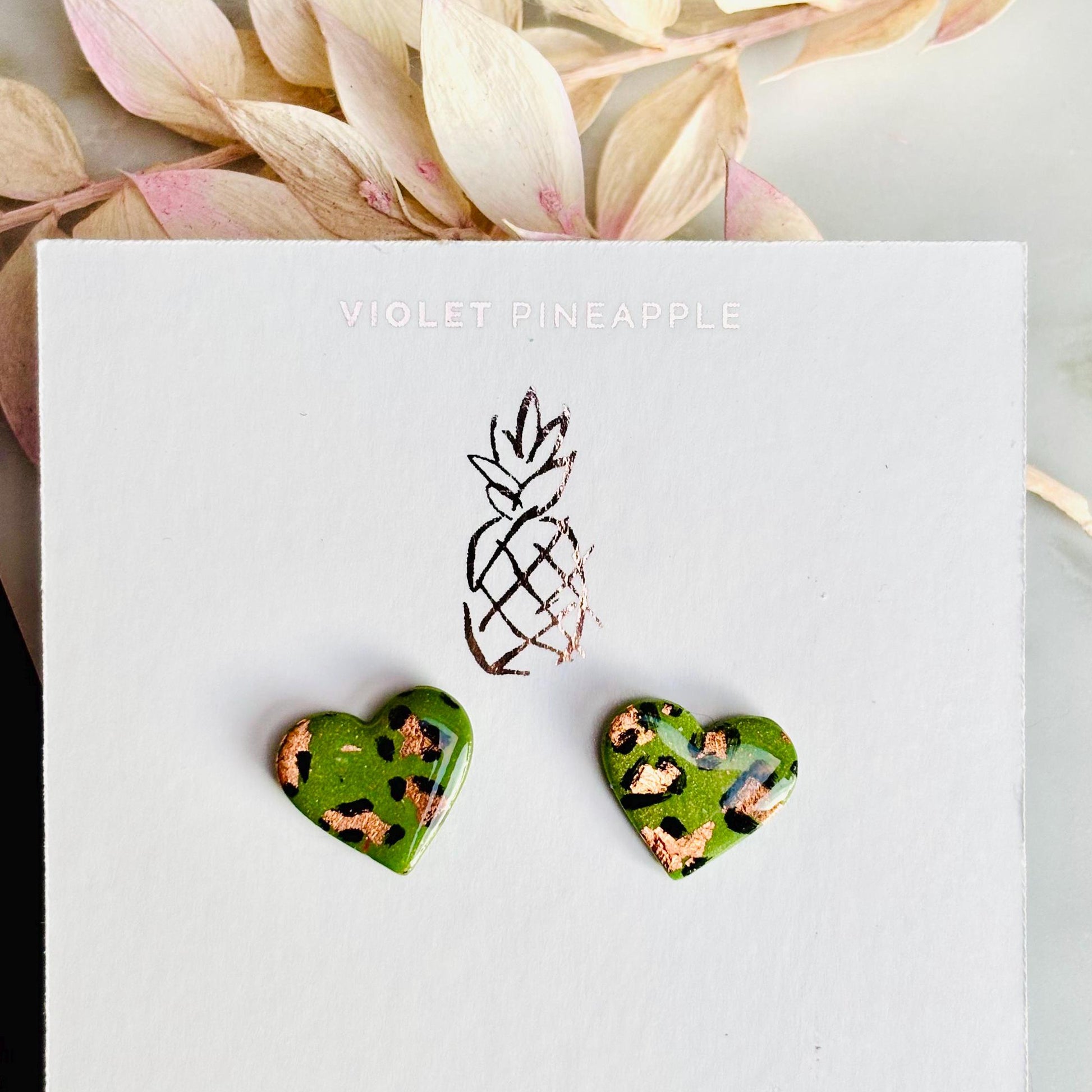 Elegant heart-shaped stud earrings with a hand-painted leopard print, handmade with polymer clay.