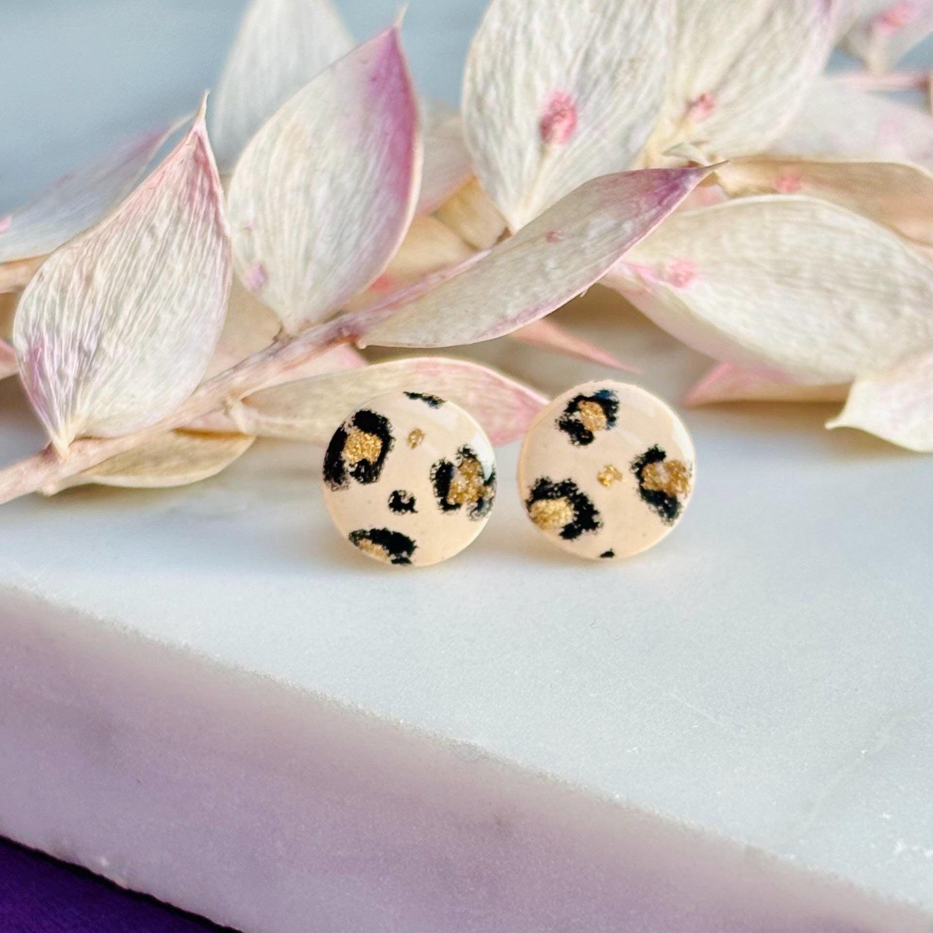 Handcrafted leopard print bracelet and stud earring set with neutral tones and gold accents. Stud earrings are 10mm x 10mm. Set includes an adjustable black corded bracelet. Packaged in a branded gift box