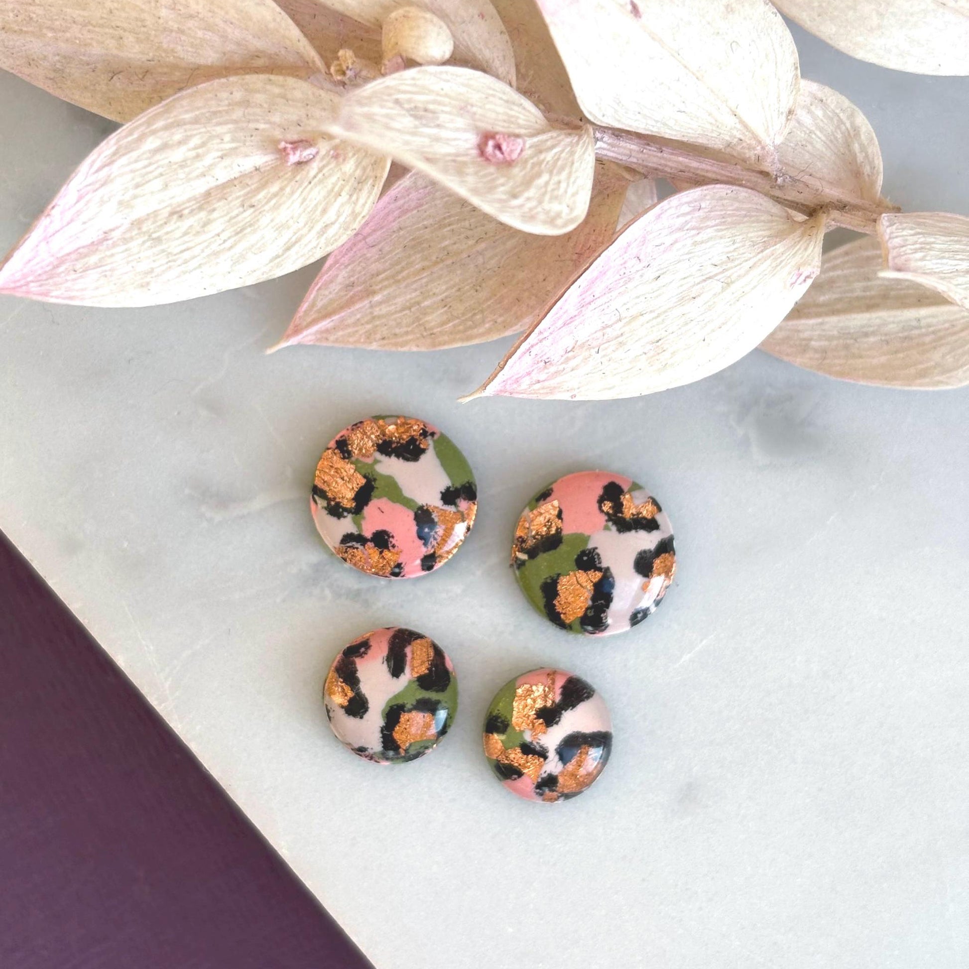 Vivid leopard print stud earrings, 10mm x 10mm, with hand-painted spots in peach, olive green, and rose gold, handmade from polymer clay.