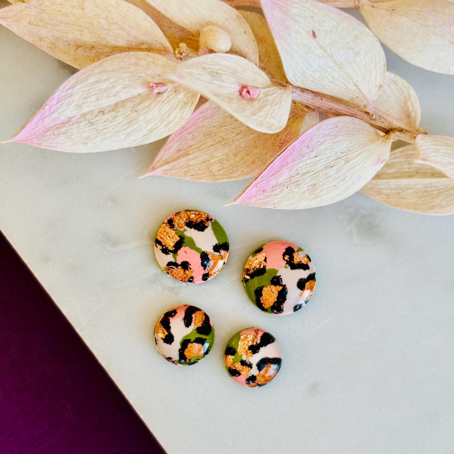 Petite leopard print stud earrings, 8mm x 8mm, with hand-painted spots in olive green and peach tones, handmade from polymer clay.