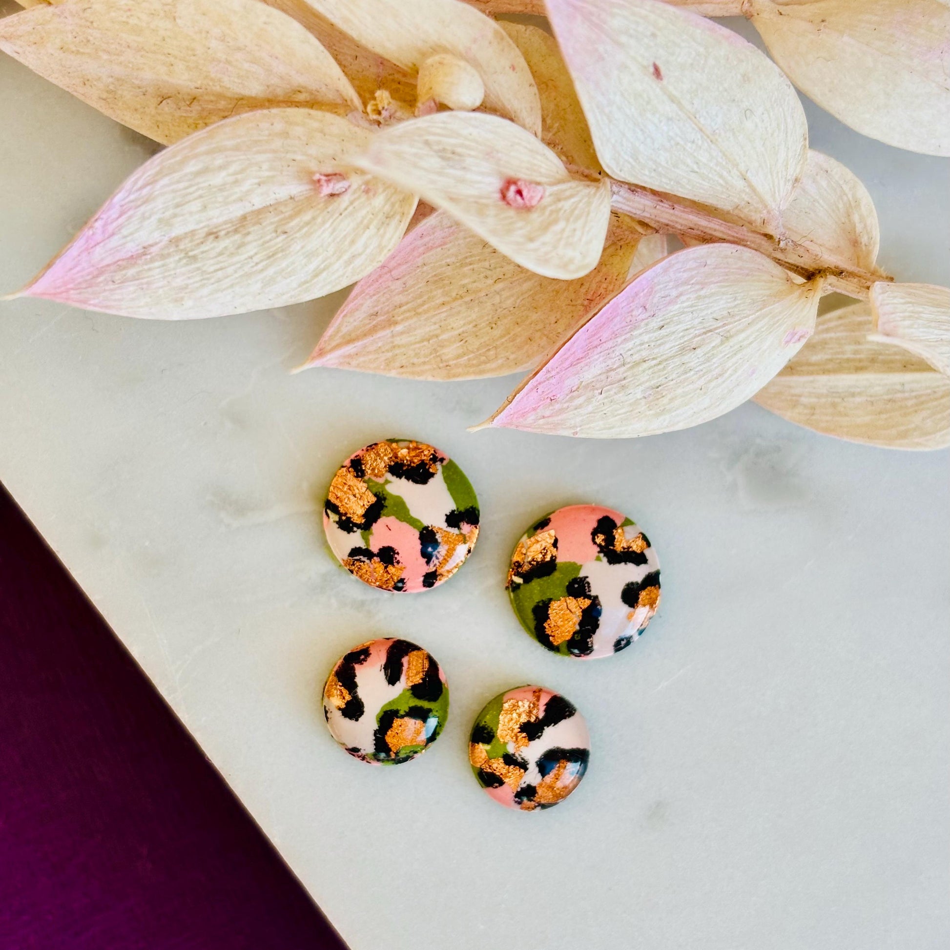 Petite leopard print stud earrings, 8mm x 8mm, with hand-painted spots in olive green and peach tones, handmade from polymer clay.