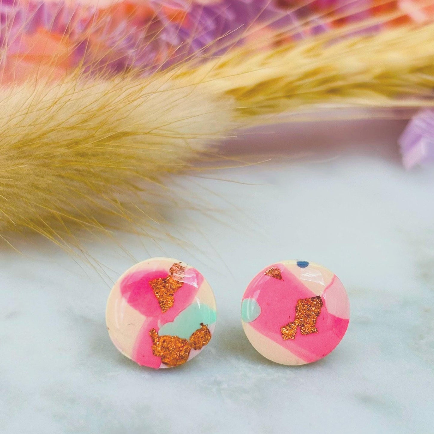 Handmade blush pink stud earrings with soft mint pastel undertones and delicate rose gold leaf detail. Finished with a glossy resin for durability and a refined look.