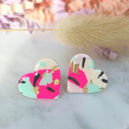 Vibrant 90s punk-inspired heart-shaped stud earrings, handmade with polymer clay. Features neon pink, mint, black ink, and gold leaf accents.