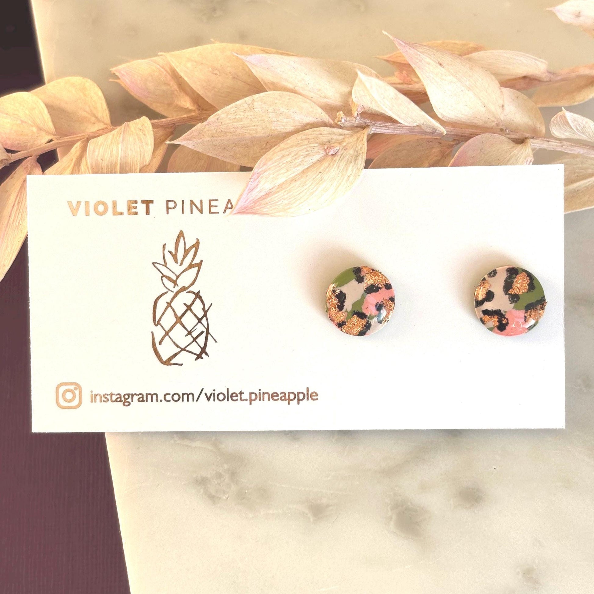 Vivid leopard print stud earrings, 10mm x 10mm, with hand-painted spots in peach, olive green, and rose gold, handmade from polymer clay.