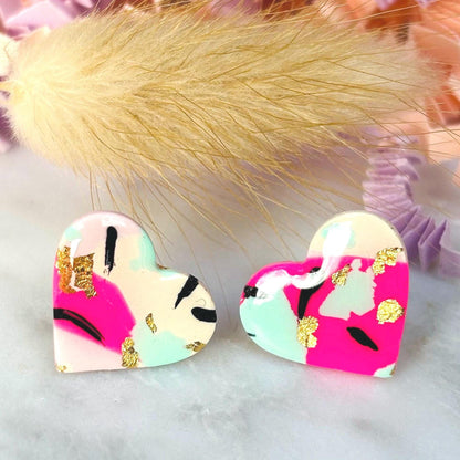 Vibrant 90s punk-inspired heart-shaped stud earrings, handmade with polymer clay. Features neon pink, mint, black ink, and gold leaf accents.