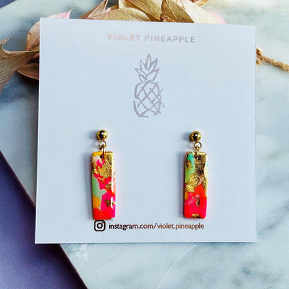 Colourful surf-inspired drop stud earrings with gold foil detail, handmade from polymer clay, featuring hypoallergenic surgical stainless steel posts and backings.