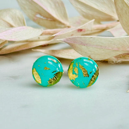 Mini teal and gold polymer clay stud earrings, with a focus on their textured surface and reflective gold details