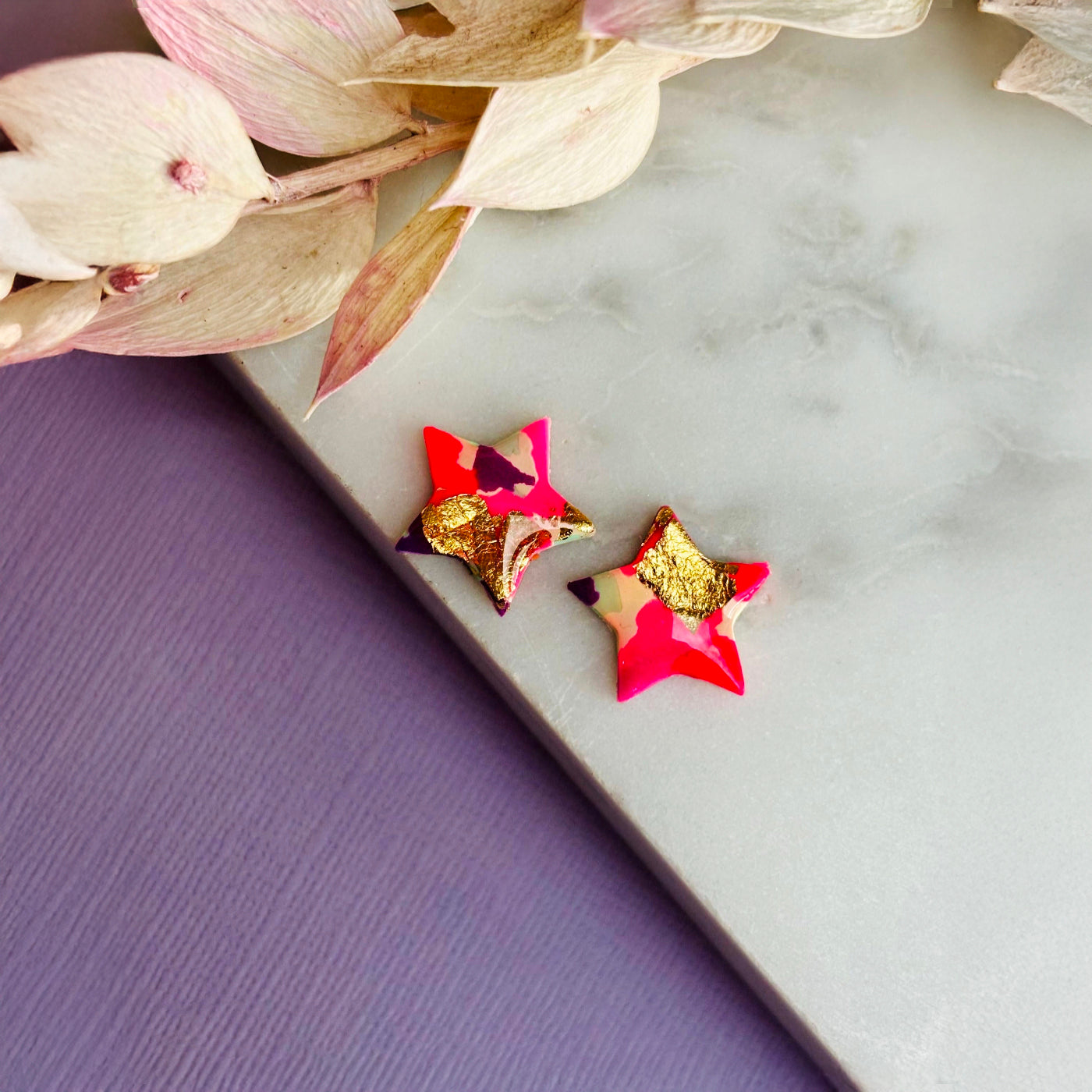 Pair of vibrant handmade star stud earrings featuring a playful mix of pink, mint, and gold colours.