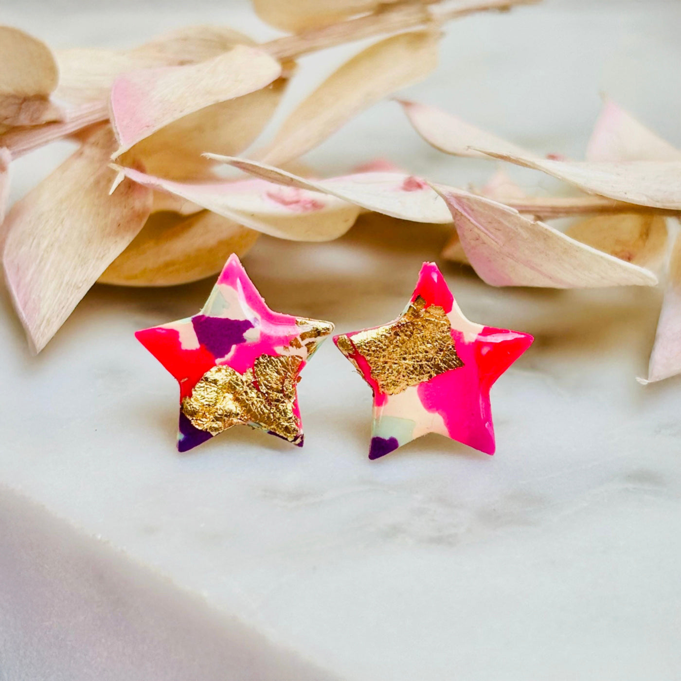 Pair of vibrant handmade star stud earrings featuring a playful mix of pink, mint, and gold colours.