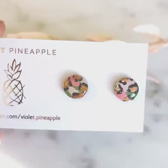 Vivid leopard print stud earrings, with hand-painted spots in peach, olive green, and rose gold, handmade from polymer clay.