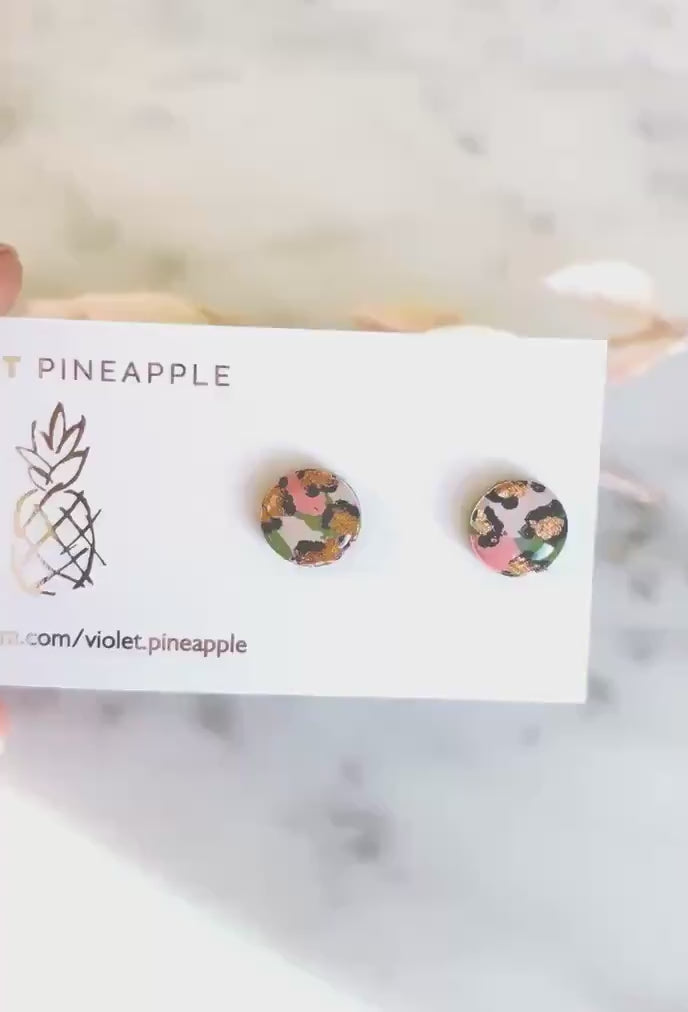 Vivid leopard print stud earrings, with hand-painted spots in peach, olive green, and rose gold, handmade from polymer clay.