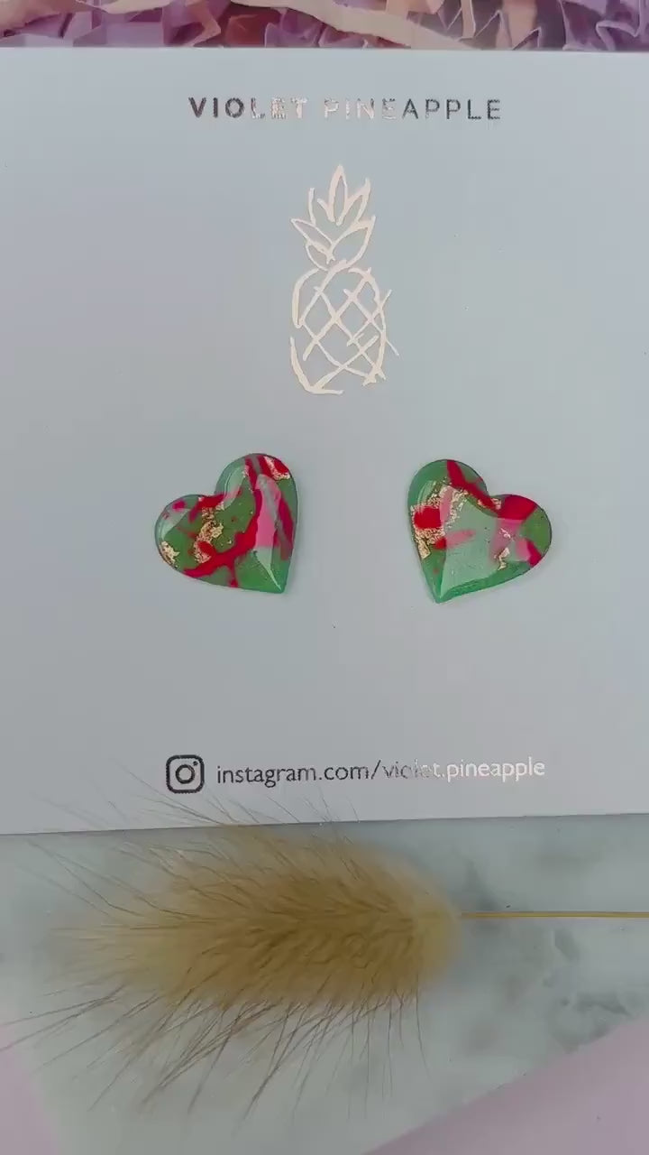 Vibrant neon pink heart-shaped stud earrings, handmade with polymer clay. Features an abstract design with gold foil accents.