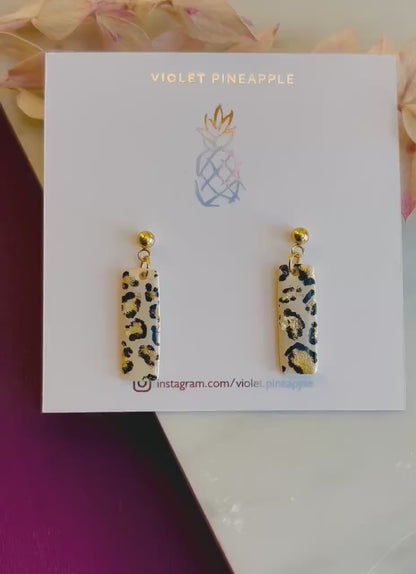 Elegant leopard print drop stud earrings with neutral tones and gold accents, hand-painted and handmade with polymer clay.