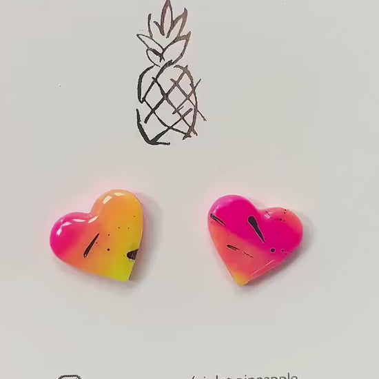 Vibrant 80s disco-inspired heart-shaped stud earrings, handmade with polymer clay. Features a bold color palette with yellow, pink, and black ink splatter