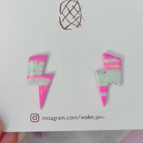 Vibrant 80s ski-inspired lightning bolt stud earrings, handmade with polymer clay. Features soft pink, mint green, and gold leaf accents.