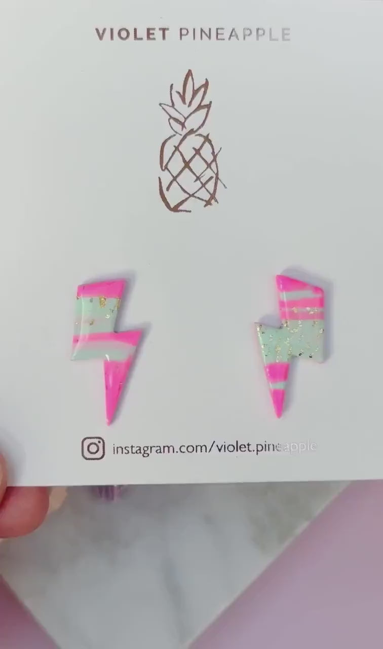 Vibrant 80s ski-inspired lightning bolt stud earrings, handmade with polymer clay. Features soft pink, mint green, and gold leaf accents.